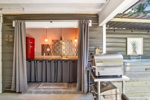 Covered outdoor kitchen with refrigerator, microwave, pizza oven, and bbq grill.