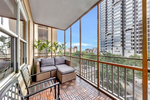 Screened balcony w/ cushioned seating, potted plants & city views for relaxing mornings