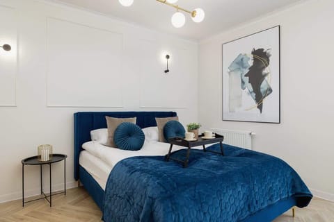A modern bedroom with a navy-blue headboard, a matching bedspread, and a stylish painting above, creating a cozy yet sophisticated ambiance.
