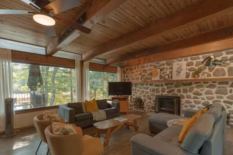 Warm living room with large windows and a rustic stone fireplace