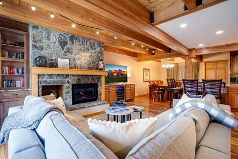 Sink into plush sofas by your crackling stone fireplace, where rustic beams meet modern comfort in this stunning open-plan retreat.