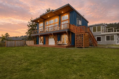 Golden-hour skies, warm cabin lights, and a spacious lawn set the scene for a peaceful Whidbey Island escape.