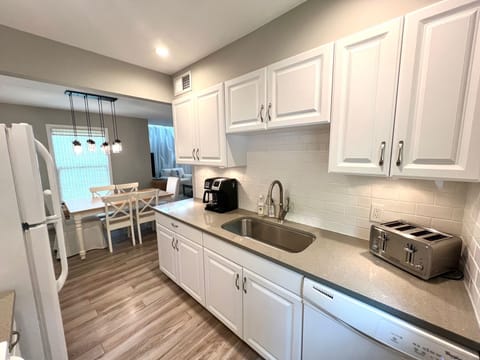 The fully equipped galley kitchen features pristine white cabinetry, a large sink, and a toaster, perfect for preparing any meal.