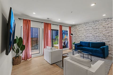 Bright open living space featuring smart flat-screen TV, designer furnishings, and patio entrance with pool view.