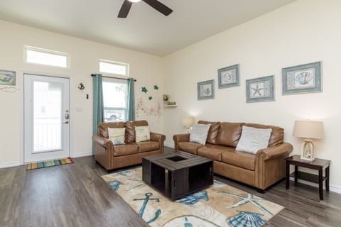 Sink into plush leather sofas beneath your ceiling fan, where nautical touches and natural light create your perfect coastal retreat.