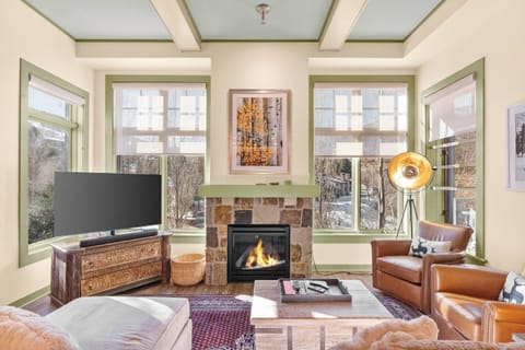 A sun filled living room with floor to ceiling windows creates an inviting space to unwind during your visit to Snowmass