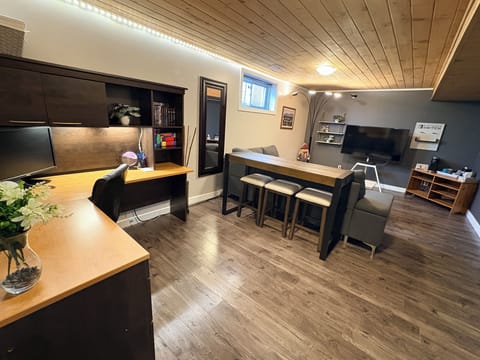 Bright, open living area with a workstation, sectional sofa, and large TV.