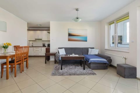 A cozy living and dining area featuring tiled floors, a blue sofa, wooden furniture, and a bright, open layout.
