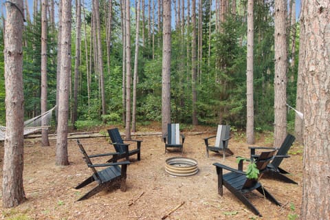 6 Adirondack chairs surround the fire pit with string lights hung around.