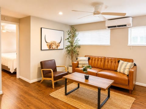 Bright, stylish living space with a modern leather sofa, smart TV, and cozy decor for relaxing.