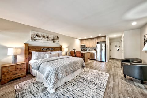 Sink into your cozy king bed surrounded by warm wood furnishings and modern amenities, with a fully equipped kitchen just steps away.