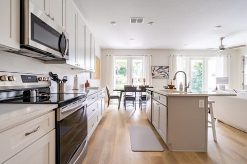 WELL-EQUIPPED KITCHEN:  Showcasing a sleek kitchen with modern amenities. From the oven and stove to the conveniently placed microwave under the overhead cabinets, every detail is designed for efficiency. The kitchen island, a focal point of functionality and style, seamlessly leads the eye to the dining table, inviting you into a space where culinary creativity meets cozy gatherings.