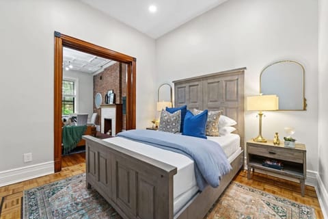 The second bedroom features a queen-size bed with a distinctive headboard, complemented by a small side table and a spacious mirror positioned overhead.