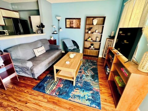 Open-concept living room with comfortable sofa and chair, Smart TV, shelving, and coffee table