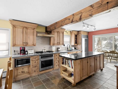 The charming kitchen has a stylish rustic vibe with beautiful natural wood cabinets and exposed wood beams