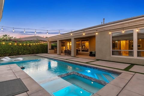 Pool and spa glow at dusk under string lights.