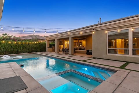 Pool and spa glow at dusk under string lights.