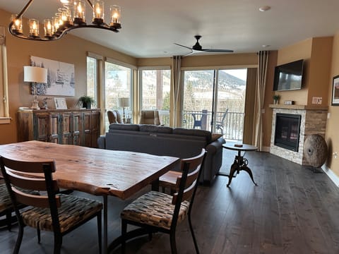 Spacious open living + dining area with mountain views, fireplace and balcony.