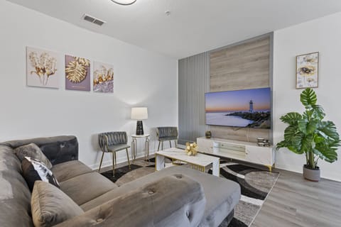 Relax in this cozy living room with a plush gray sectional and a sleek coffee table that enhance the contemporary decor. The soft lamp light creates an inviting atmosphere, and the large window reveals a lovely scenic view.