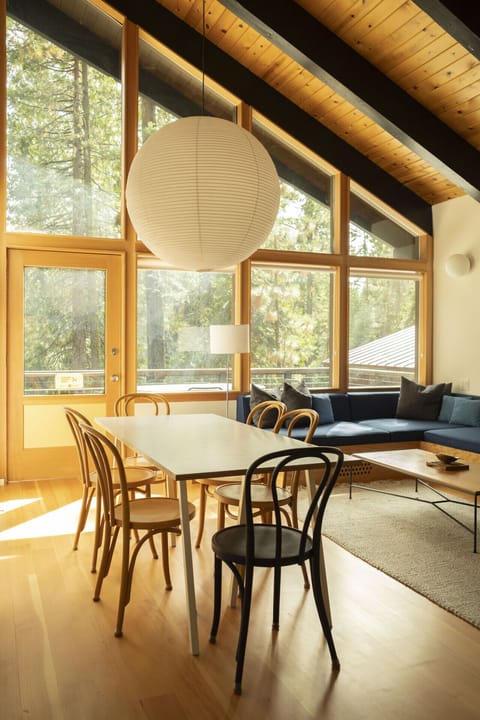 Open concept living room with custom built-in sectional sofa, large dining table, gas fireplace and large windows allowing for lots of natural light.