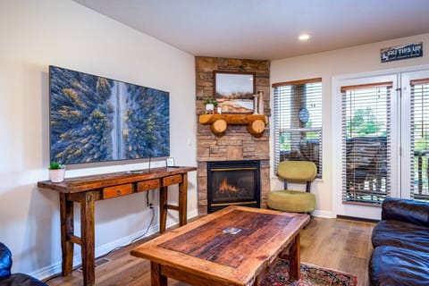 Experience the cozy living room, outfitted with plush seating, a fireplace, an expansive smart TV, and patio doors that frame the breathtaking mountain vistas.