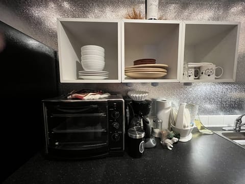 Kitchen counter with mini oven, coffee maker with coffee, dishes and glassware. 