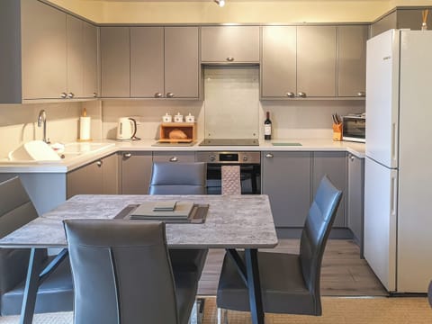 Kitchen/diner with bottle of wine and homemade bread | Cysgod Y Coed, Llanbedr