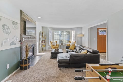 comfortable leather couch, accent chairs, decorative fireplace and  65" smart TV