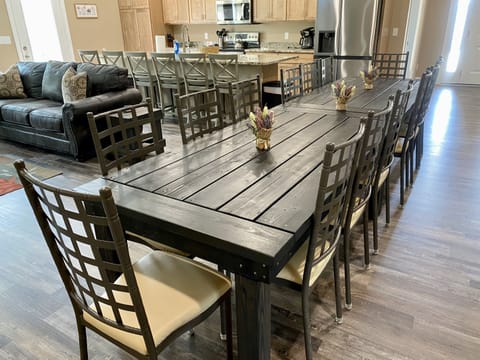 Large custom build dining table seats 14 with 6 island seats on an open kitchen/dining/living space.