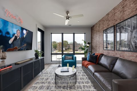 Inviting designer furnished living space featuring a comfortable sleeper sofa, a Smart TV for entertainment and a private covered balcony.