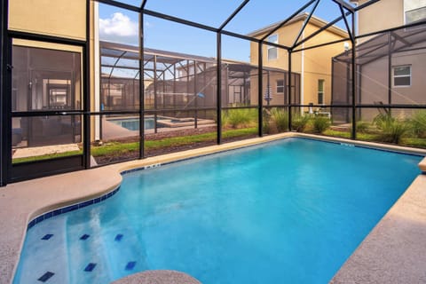 Step outside to your private oasis featuring a sparkling pool surrounded by a sleek screened enclosure, inviting you to relax in the sun. Lush greenery peeks through, enhancing the tranquil ambiance of your vacation home.