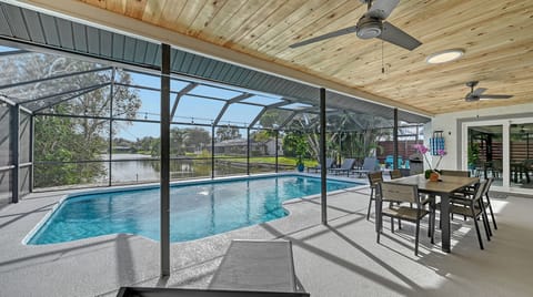 Screened pool area with outdoor dining table and chairs set under the enclosure
