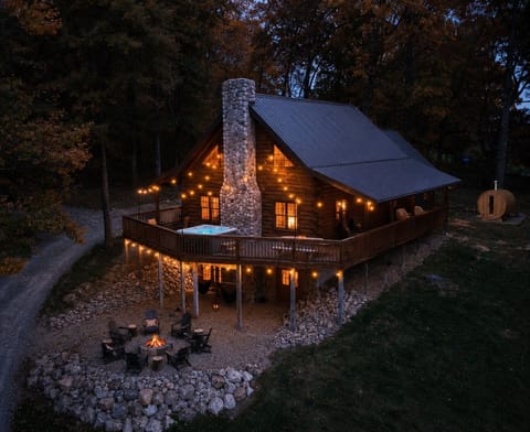 Discover your woodland retreat: a stunning Hocking Hills cabin nestled in lush greenery, featuring a spacious deck and rustic stone accents.