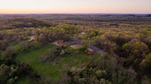 Aerial view at sunset of cabins nestled in a lush, rolling forest