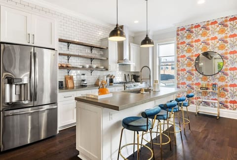 A well-appointed and roomy kitchen featuring a generous kitchen island boasting bar seating for four, accompanied by a convenient beverage cart.