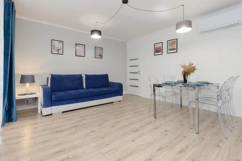 A modern living room with a blue sofa, a white coffee table, and minimalistic decor in a bright, airy space.
