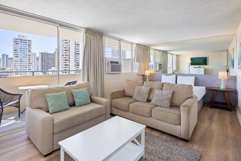 Sink into soft sofas and enjoy sweeping city views through floor-to-ceiling windows. Your bright, open-plan retreat features a cozy bed and modern touches for an unforgettable stay.