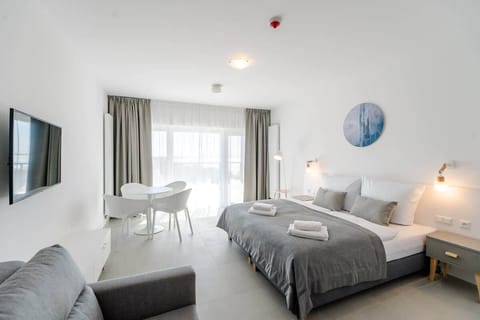 A bright bedroom with a double bed, gray bedding, and bedside lamps, creating a cozy and inviting atmosphere.
