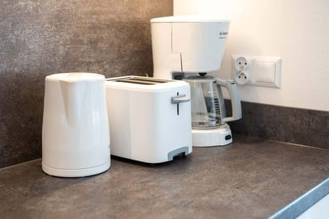 A coffee and tea station on the kitchen countertop, featuring a kettle, a toaster, and a coffee machine, adding convenience to the space.
