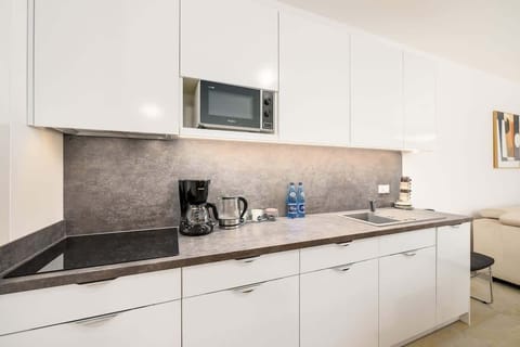 A kitchen with sleek white cabinetry, a black backsplash, and modern appliances, designed for both functionality and aesthetics.
