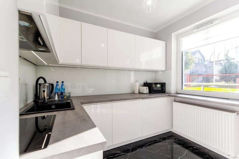 A sleek kitchen with white cabinetry, modern appliances, and a clean design, perfect for cooking and hosting.
