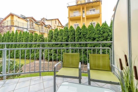 A balcony view overlooking a green hedge and neighboring buildings, offering a private outdoor space.

