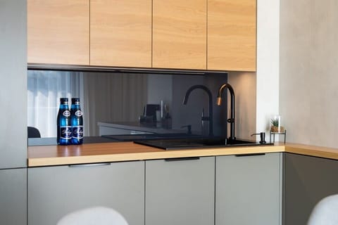The modern kitchen with wooden cabinetry, a dark countertop, and small appliances like a kettle and coffee machine. The dining area is partially visible.







