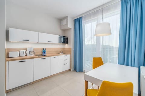 A modern kitchen and dining area with clean white finishes, blue accents, and a functional layout.
