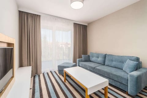 Bright living room with a comfortable sofa, dining area, and direct access to the private balcony.