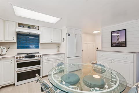 - Bright white kitchen with modern stove refrigerator dishwasher and cabinets  
- Glass dining table with padded chairs provides a stylish space for meals  
- Fully stocked for cooking family dinners during your St Augustine getaway  
