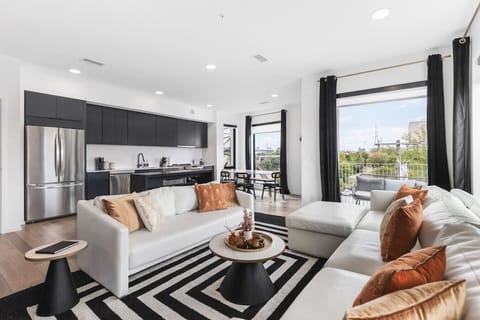 Open floor plan from the kitchen to living room, equipped with new furnishings, plenty of natural light, and the balcony overlooking the Cumberland river.