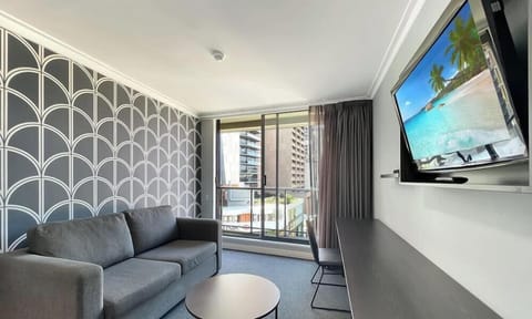 Living room with wall-mounted TV, sofa seating, and city outlook.