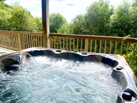 hot tub for 5-6 people located on lower deck, surrounded by trees and privacy 