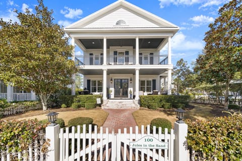 Charming Southern-style home with classic white columns and wraparound porches, nestled among mature trees in a peaceful neighborhood setting.